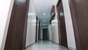 A long, narrow hallway with wooden doors on both sides and a tiled floor. - Sonar Bangla Guest House (Kolkata)
