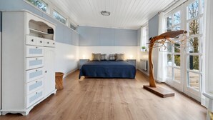Ein Schlafzimmer mit Bett, Schminktisch, Fenster und einem einzigartigen Holzkunstwerk.