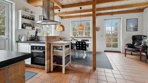 Eine moderne Küche mit Backofen, Holzbalken und einem Essbereich mit einem schwarzen Stuhl und einem Tisch.