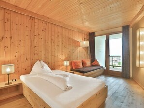 Una stanza con pannelli di legno, un letto, una panca e una finestra con vista.