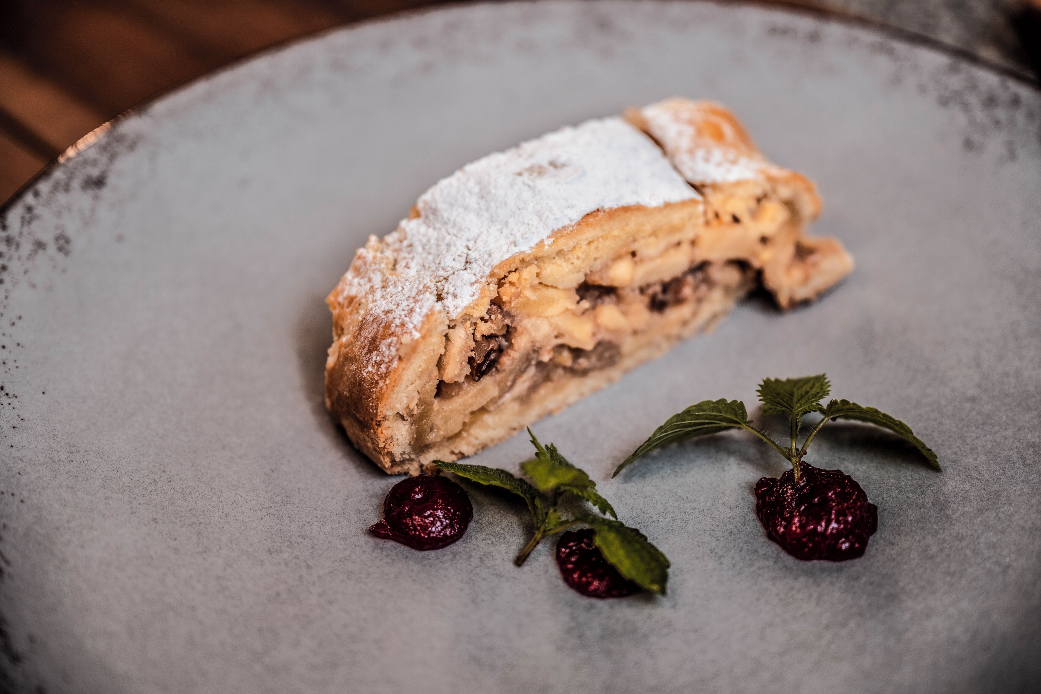 A slice of layered pastry on a plate with powdered sugar and mint leaves.