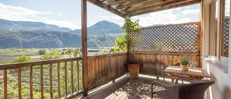 Una terraza de madera con una mesa y sillas, con vistas a un valle y montañas.