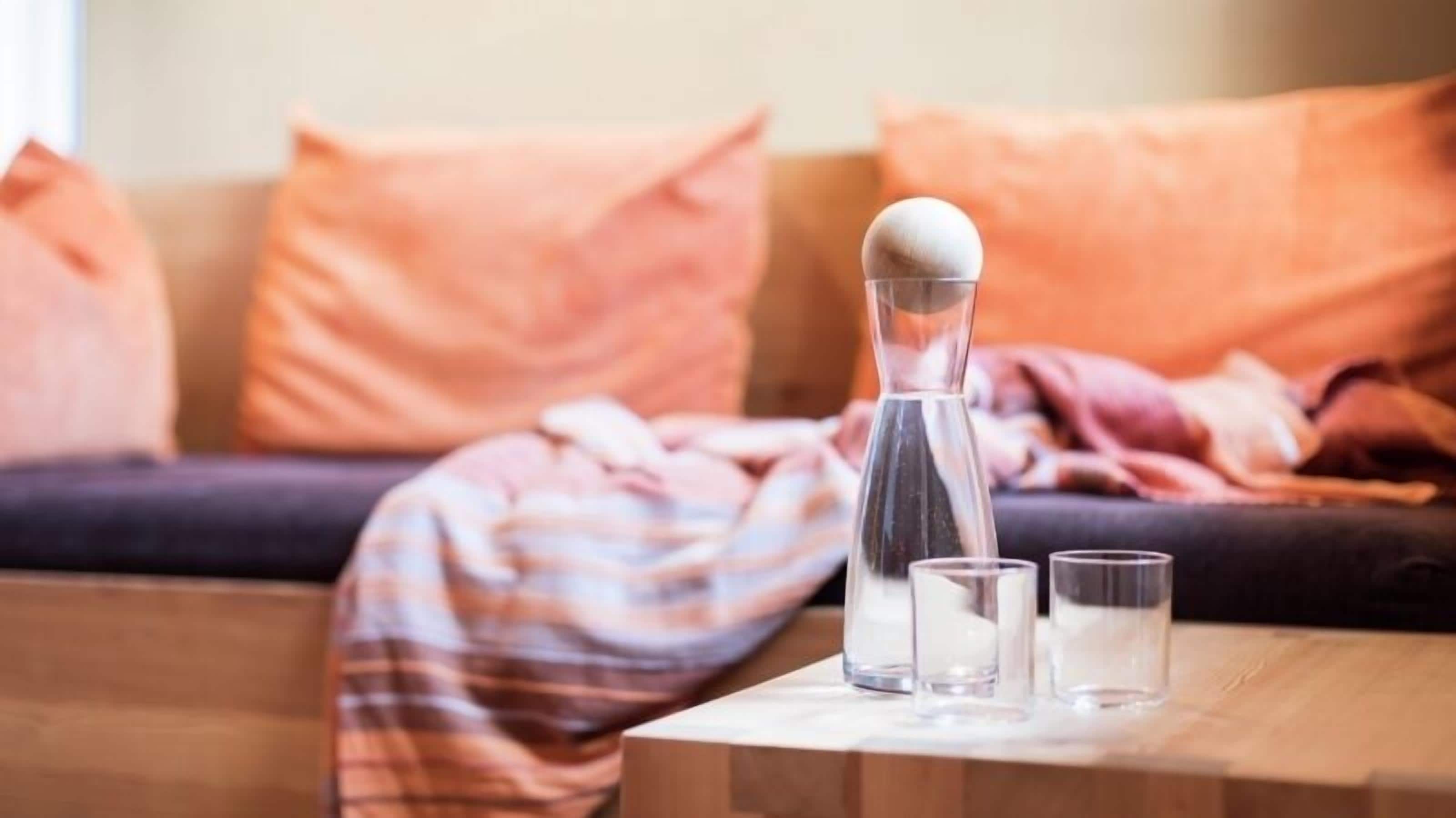 A room with a sofa, a coffee table, a bottle, and two glasses.