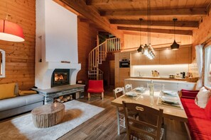 A cozy cabin interior with a fireplace, wooden walls, a dining area, and a staircase. - Chalet Soleada With Fireplace and Terrace for 5 (Mesocco)