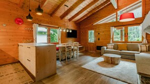 Ein Holzblockhaus-Interieur mit Essbereich, Sofa und Küchenzeile.