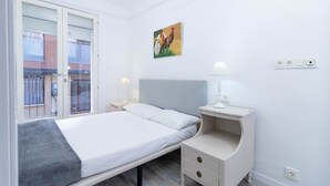 Een slaapkamer met een bed, nachtkastje en een schilderij aan de muur.