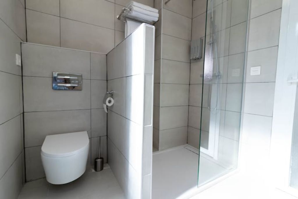 A modern bathroom with a toilet, a glass shower enclosure, and a towel rack.