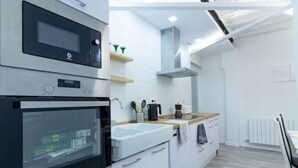 Een moderne keuken met inbouwapparatuur, een wit aanrecht en een houten vloer.