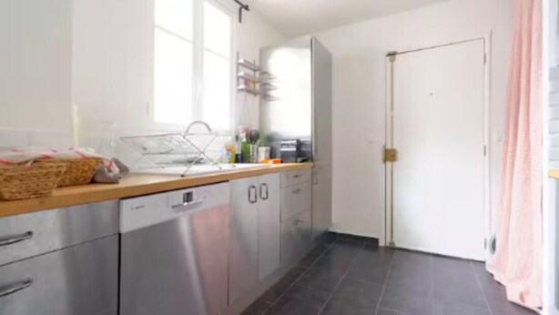 Una cocina moderna con electrodomésticos de acero inoxidable, una encimera de madera y un ventanal que proporciona luz natural.