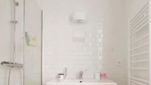 Un baño con ducha, lavabo y espejo.