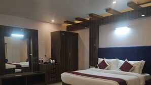 A modern bedroom with a large bed, a wardrobe, a mirror, and a desk. - Arunya Hotel & Resort (Rajgir)