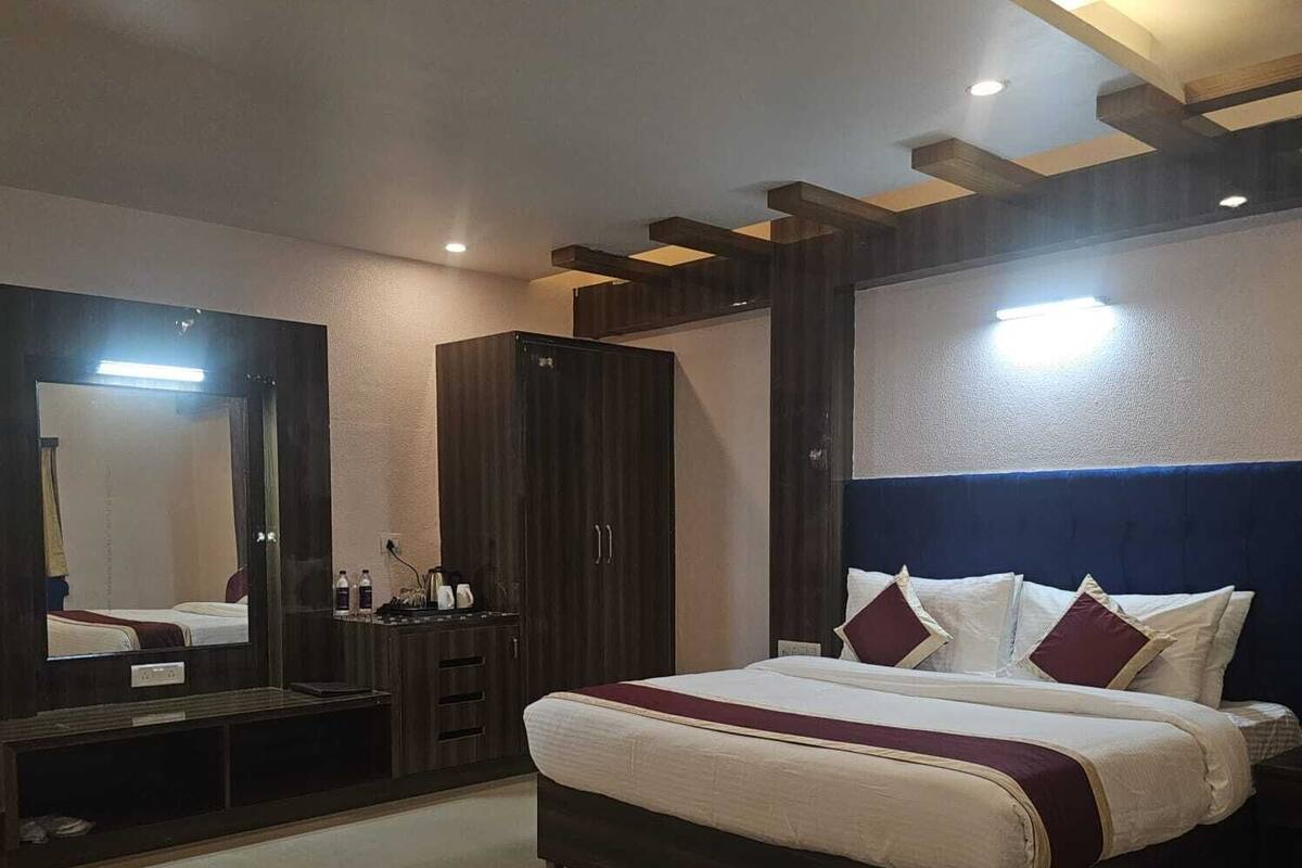 Quarto moderno com cama grande, guarda-roupa, espelho e escrivaninha.