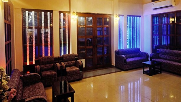 A spacious lobby with a high ceiling, a chandelier, and a seating area with sofas and armchairs. - Arunya Hotel & Resort (Rajgir)