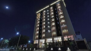 Un hotel de varios pisos con ventanas iluminadas y una entrada bien iluminada.