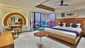 Habitación de hotel moderna con una cama grande, un escritorio, un espejo redondo y vistas a la ciudad.