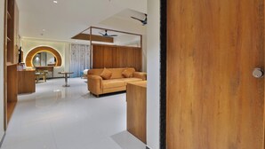 Un interior moderno con una puerta de madera, un sofá, una zona de comedor y un ventilador de techo.