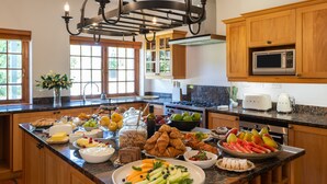 A kitchen island with various food items and a microwave above it. - Navarre Residence (Stellenbosch)