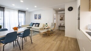 Ein modernes Wohnzimmer mit Essbereich, einer Couch, einem Couchtisch und einer Lampe.