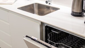 Eine Küche mit Spüle aus Edelstahl, einem Geschirrspüler von Bosch und einer Kaffeemaschine auf der Arbeitsfläche.
