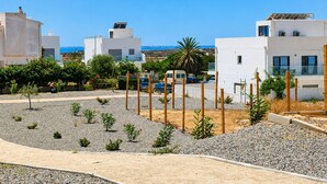 A coastal residential area with modern white buildings, a clear blue sky, and a view of the sea. - Fully equipped, by the sea in a quiet residential area near Olhão. (Moncarapacho)