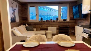 Uma sala de estar aconchegante com um sofá, cadeiras e uma mesa de jantar posta com pratos.
