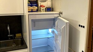 Uma cozinha compacta com geladeira embutida, pia e bancada pequena.