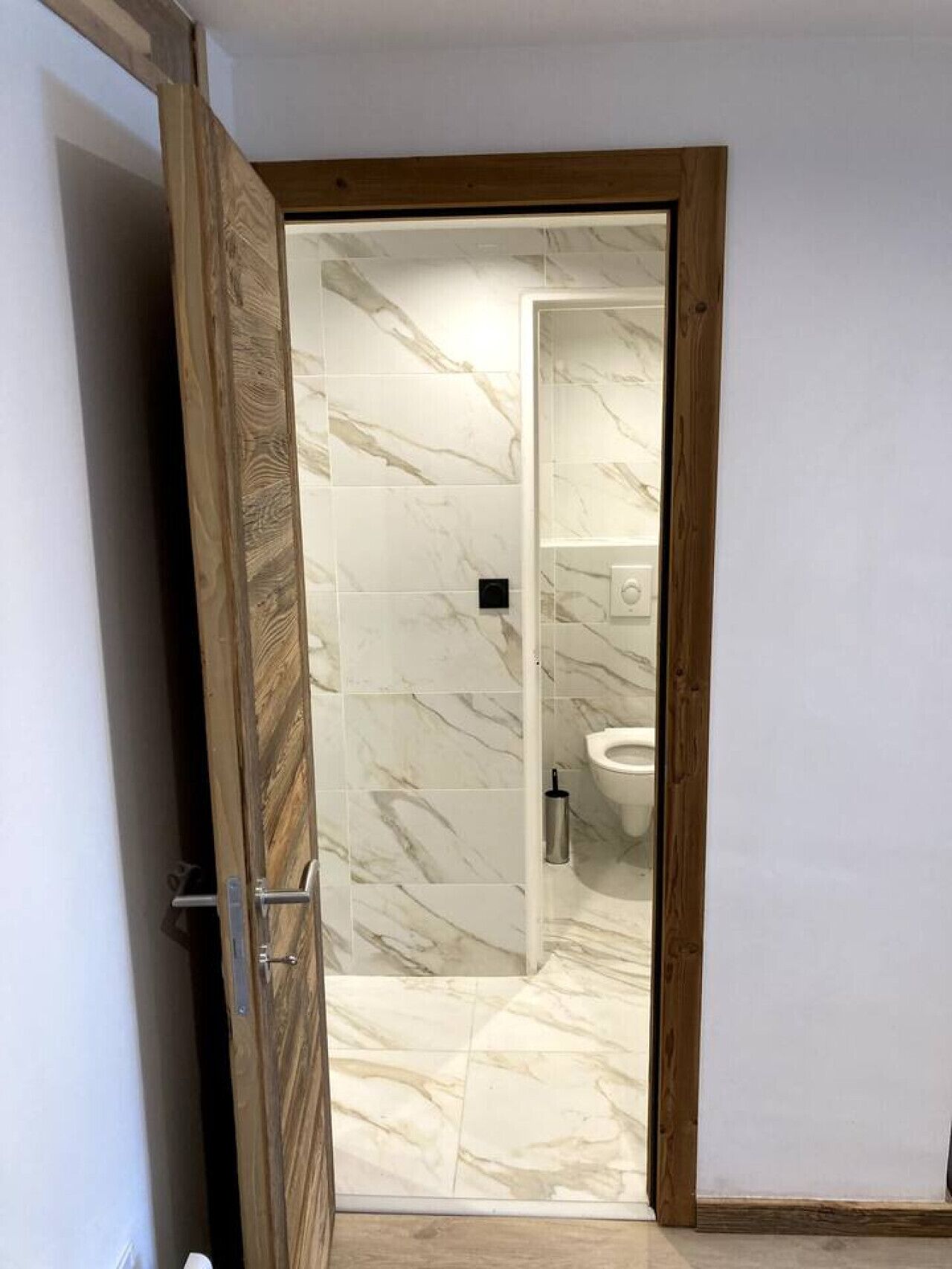 Une salle de bain carrelée de marbre, avec des toilettes et un espace douche.