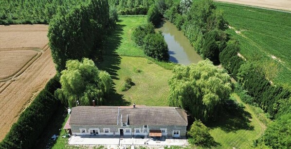An aerial view of a house with a tiled roof, surrounded by fields and a river. - Le Moulin Saint-Nicolas (Maizy)