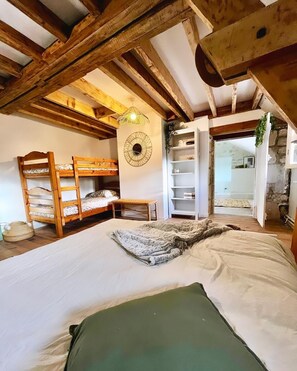 A bedroom with a large bed, wooden bunk beds, a circular wall decoration, and a white wardrobe. - Le Moulin Saint-Nicolas (Maizy)