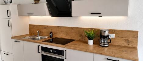 A modern kitchen with a built-in oven, a coffee maker, and a plant on the countertop.
