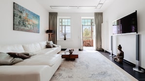 Een moderne woonkamer met een witte bank, een salontafel en een groot abstract schilderij.