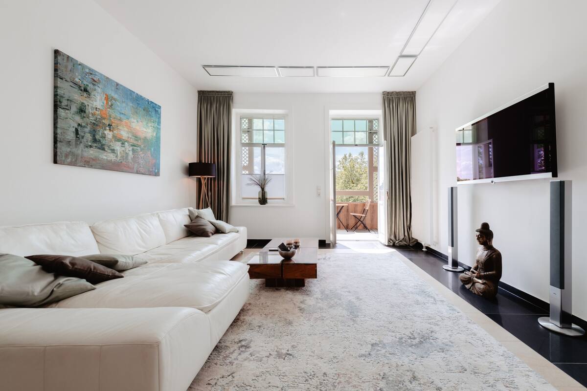 A modern living room with a white sofa, a coffee table, and a large abstract painting.