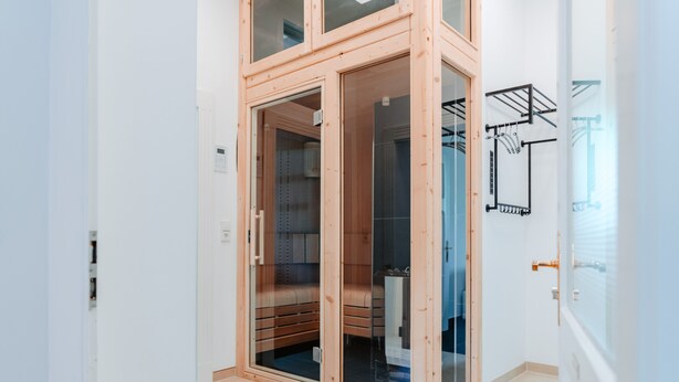 Een moderne kamer met een houten garderobe, een glazen deur en een handdoekhouder aan de muur.