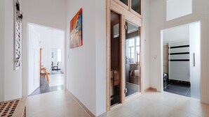 Een ruime hal met een houten deur die leidt naar een kamer met een groot raam.