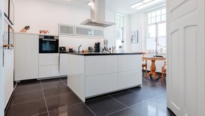 Een moderne keuken met witte kasten, een inbouwoven en een groot eiland met een zwart aanrecht.