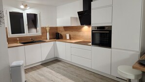 A modern kitchen with white cabinets, a wooden countertop, a built-in oven, and a window with a view. - A 250 m de la Plage de Favone, Appartement vue mer Avec Terrasse de 30m2 (Conca)