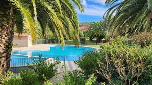 A swimming pool surrounded by lush greenery and palm trees. - A 250 m de la Plage de Favone, Appartement vue mer Avec Terrasse de 30m2 (Conca)