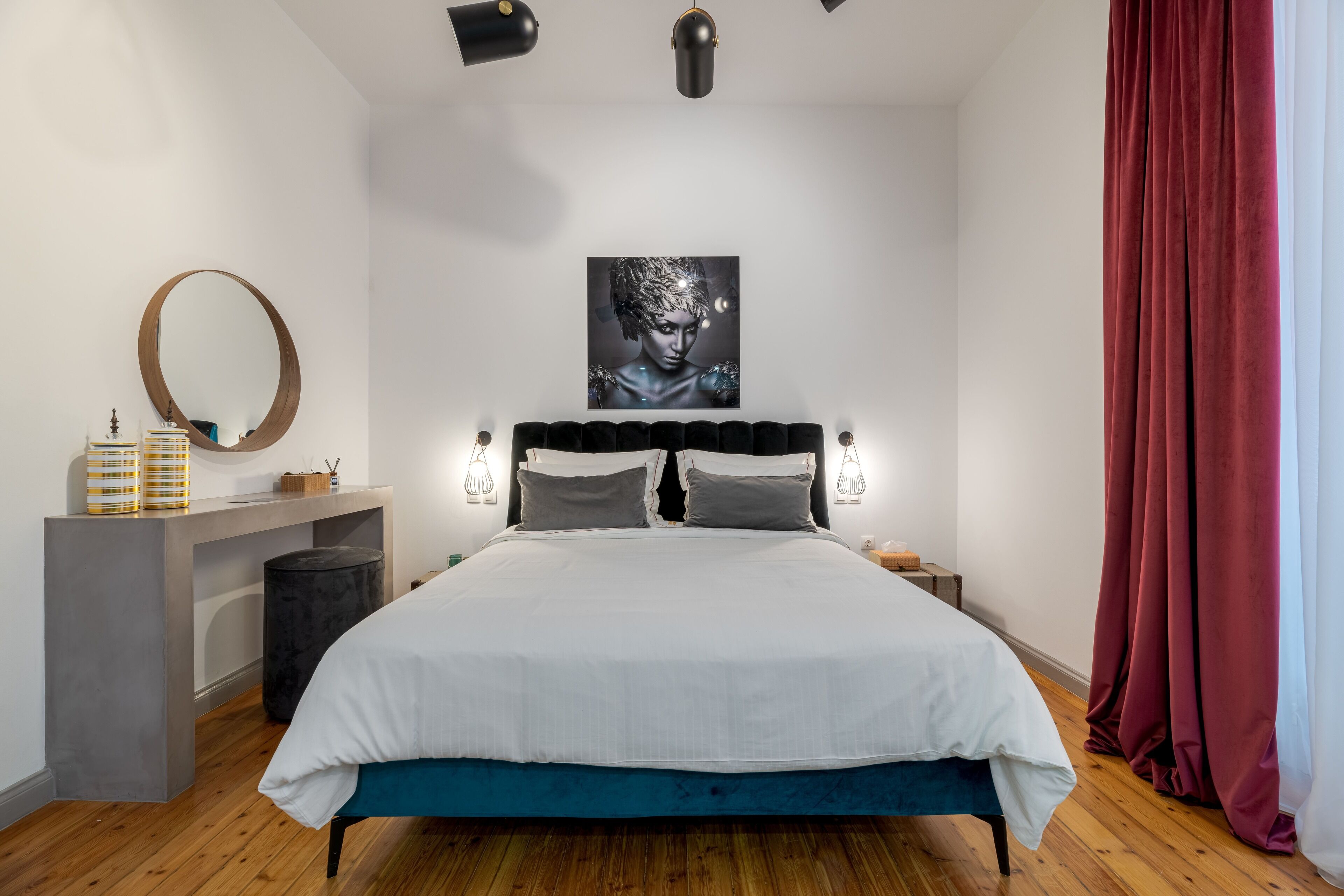 A modern bedroom with a bed, bedside tables, a mirror, and a wall-mounted artwork.