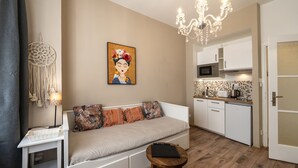 A compact living space with a sofa, a small table, a wall-mounted artwork, a kitchen area with a microwave, and a chandelier. - Old Town - Studio Petrin Tower (Prague)