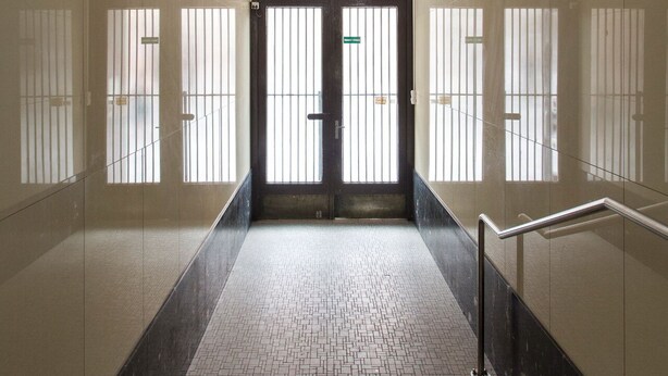 A hallway with a black door, a metal handrail, and a tiled floor. - Old Town - Studio Petrin Tower (Prague)
