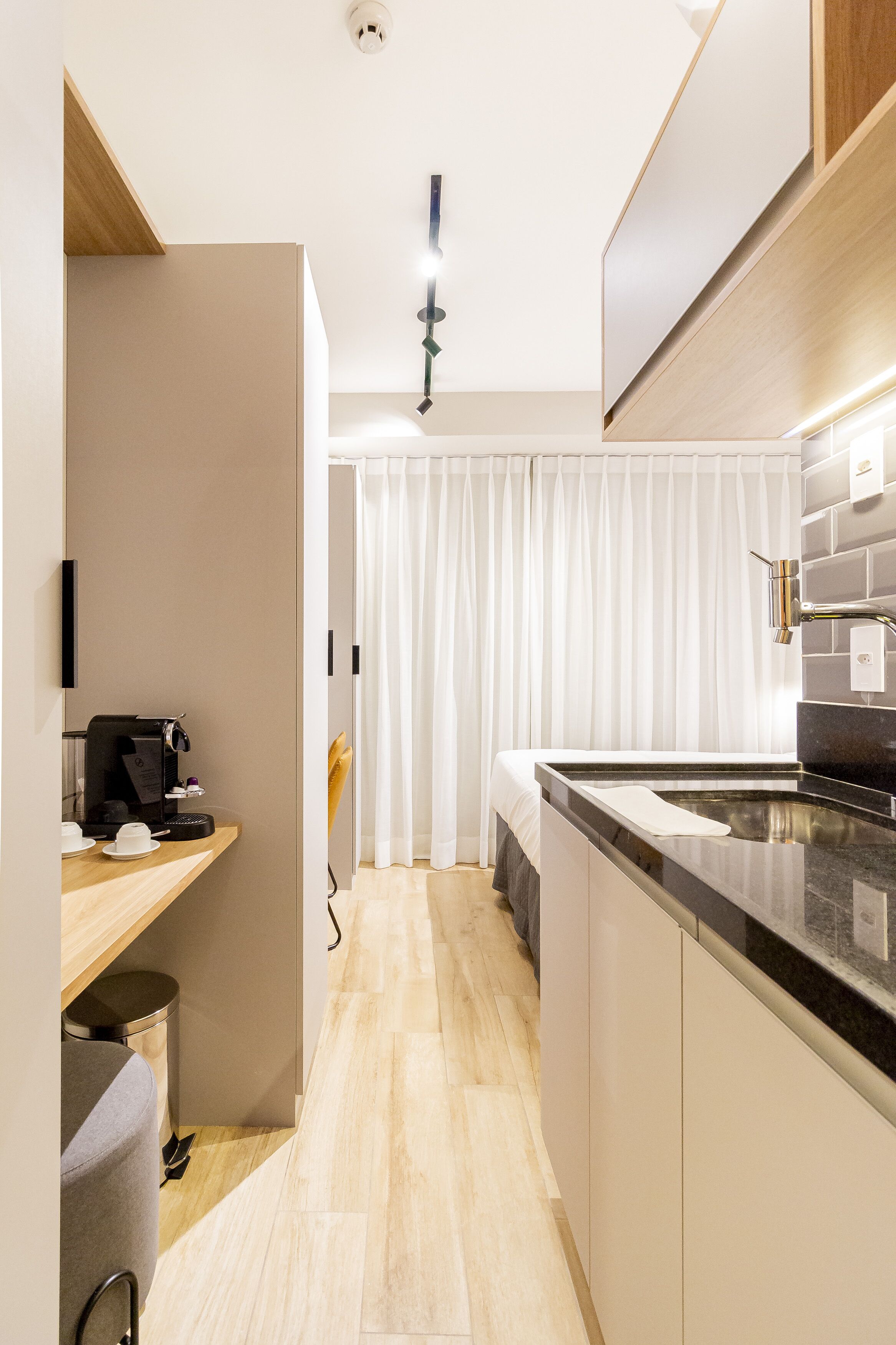 Una cocina moderna con encimera negra, armarios blancos y techo de madera.