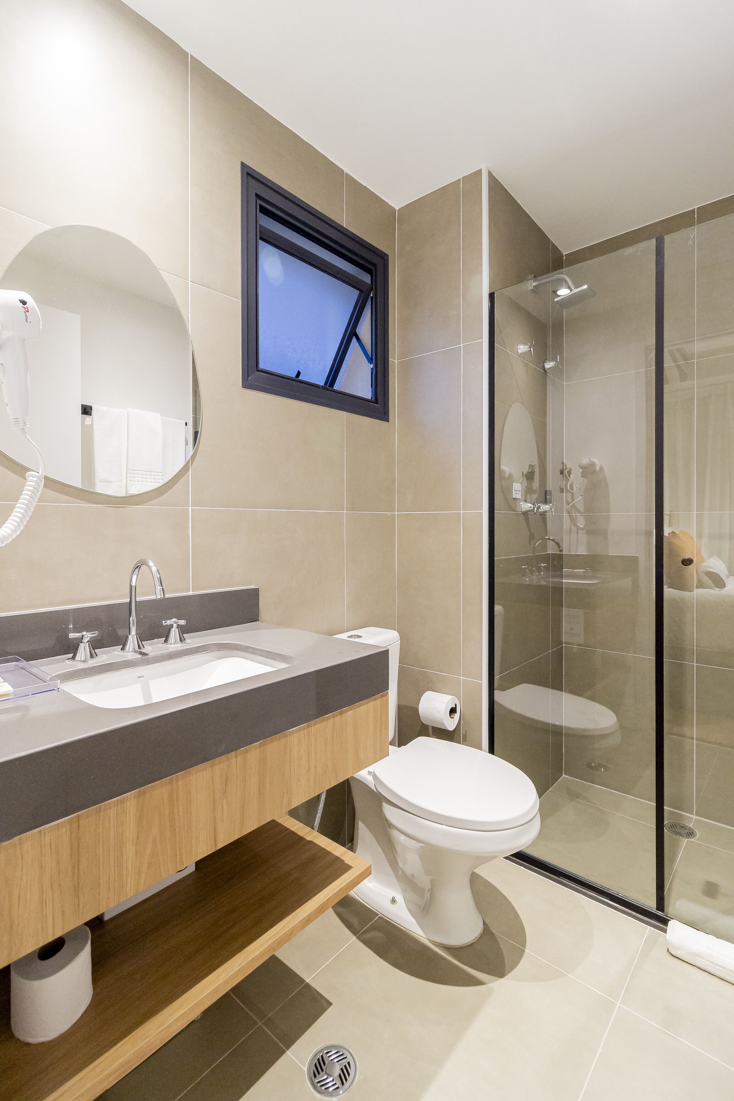 Ein modernes Badezimmer mit einem Waschtisch mit zwei Becken, einer Toilette, einer Duschkabine aus Glas und einem großen Spiegel.