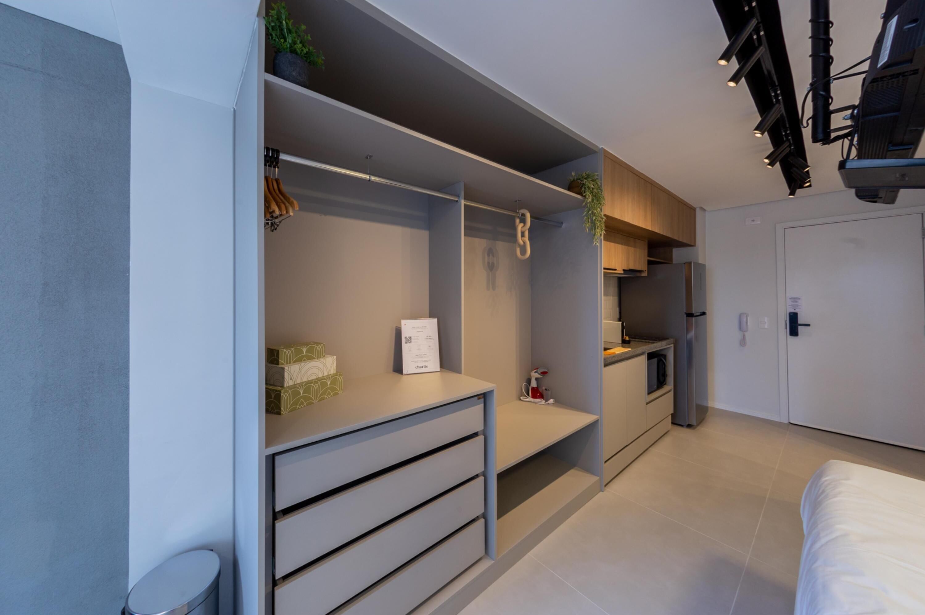A modern bedroom with a built-in wardrobe, a small kitchenette, and a bed.