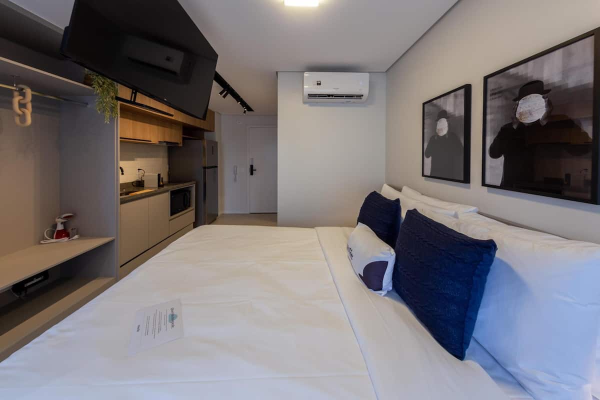 Ein Hotelzimmer mit Bett, Schreibtisch, einer Küchenzeile und einer Klimaanlage.