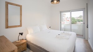 Un dormitorio con cama, mesita de noche, lámpara y vistas a través de una puerta corrediza de cristal.