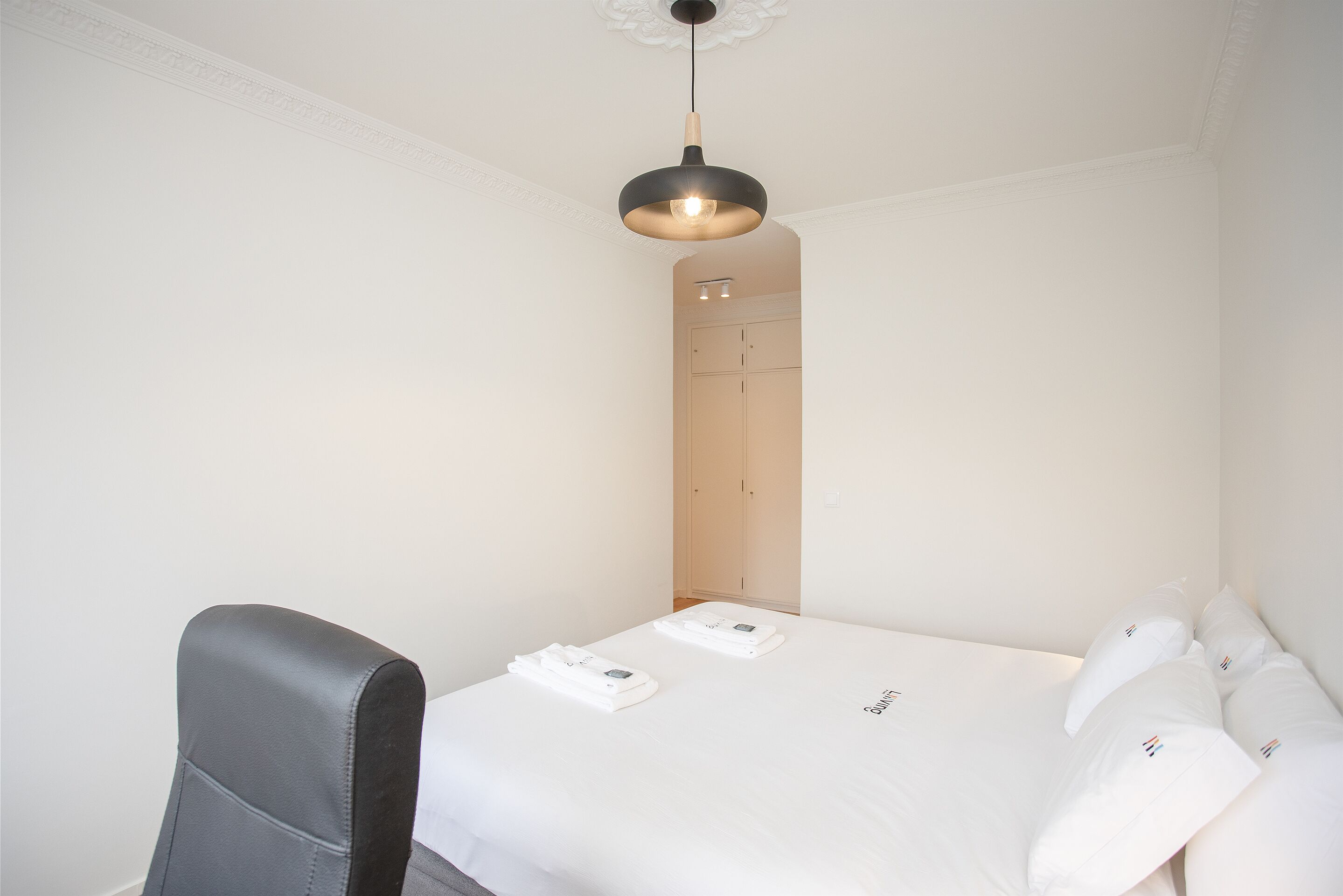 Ett hotellrum med en säng, en stol och en garderob.