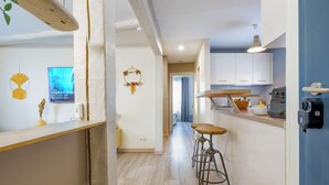 Une cuisine moderne avec des meubles blancs, une machine à café noire et un plan de travail en bois.
