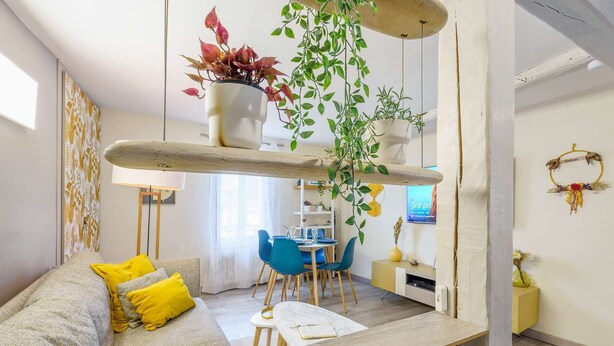Un salon moderne avec un canapé, une table à manger et des plantes suspendues.