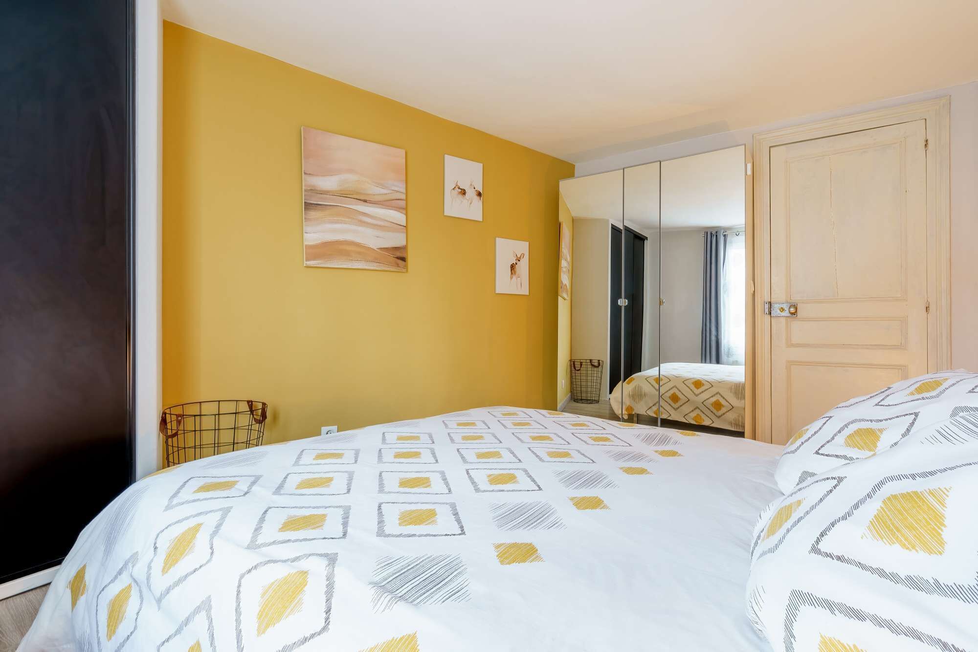 Un dormitorio con cama, armario y espejo.