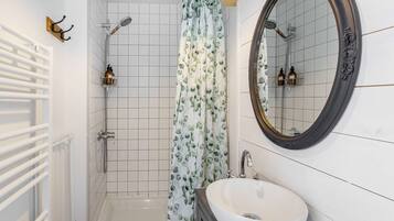 Ein Badezimmer mit einer weißen Badewanne, einer Dusche, einem Waschbecken und einem Spiegel.
